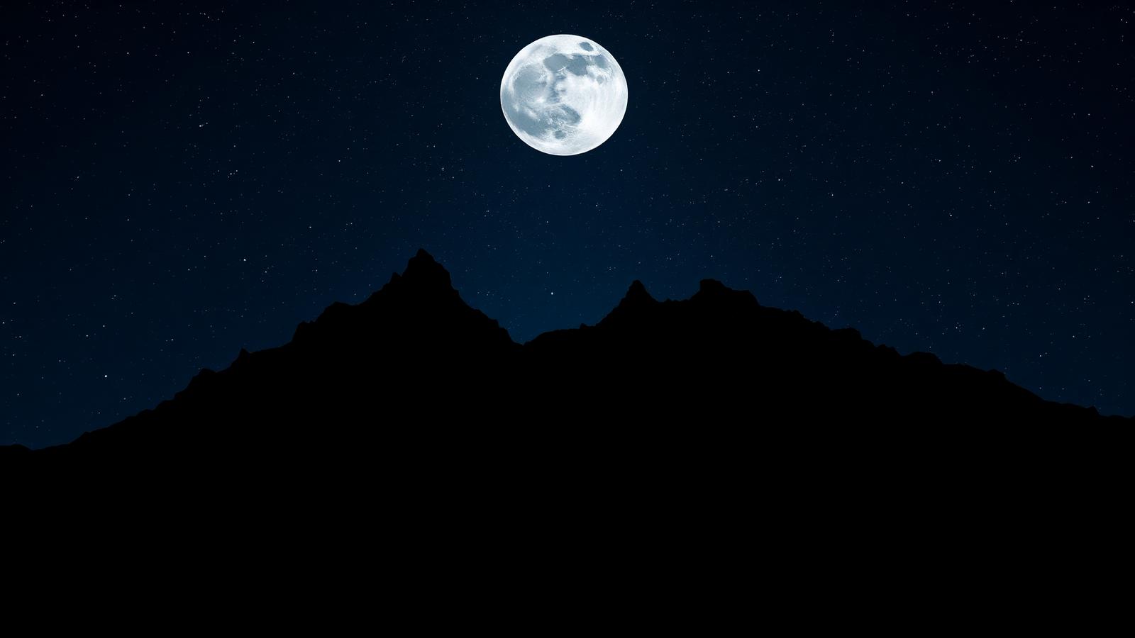 Mountain silhouette beneath a full moon and starfield